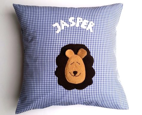 Kinderkissen Kissen mit kariertem Design, auf dem ein Löwenkopf und der Name "JASPER" appliziert sind.